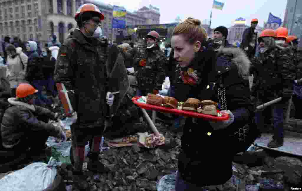 A woman carries sandwiches as anti-government protesters gather in Independence Square, central Kyiv, Feb. 19, 2014.