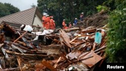 Petugas pemadam kebakaran mencari penyintas di lokasi tanah longsor di Asaminami, Hiroshima (22/8).