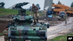 FILE - Turkish soldiers on an armored personnel carrier secure a staging area for troops preparing their tanks to enter combat and join a military offensive on a Kurdish-held enclave in northern Syria, in Hatay province, Turkey, near the the border with 