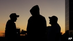 ARCHIVO - Migrantes salvadoreños hablan mientras se preparan para partir hacia la frontera de Estados Unidos con otros en una caravana, en San Salvador, El Salvador, al amanecer del miércoles 16 de enero de 2019.