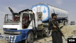 Pasukan keamanan Pakistan menjaga truk tangki bahan bakar NATO setelah terjadinya serangan oleh militan bersenjata.