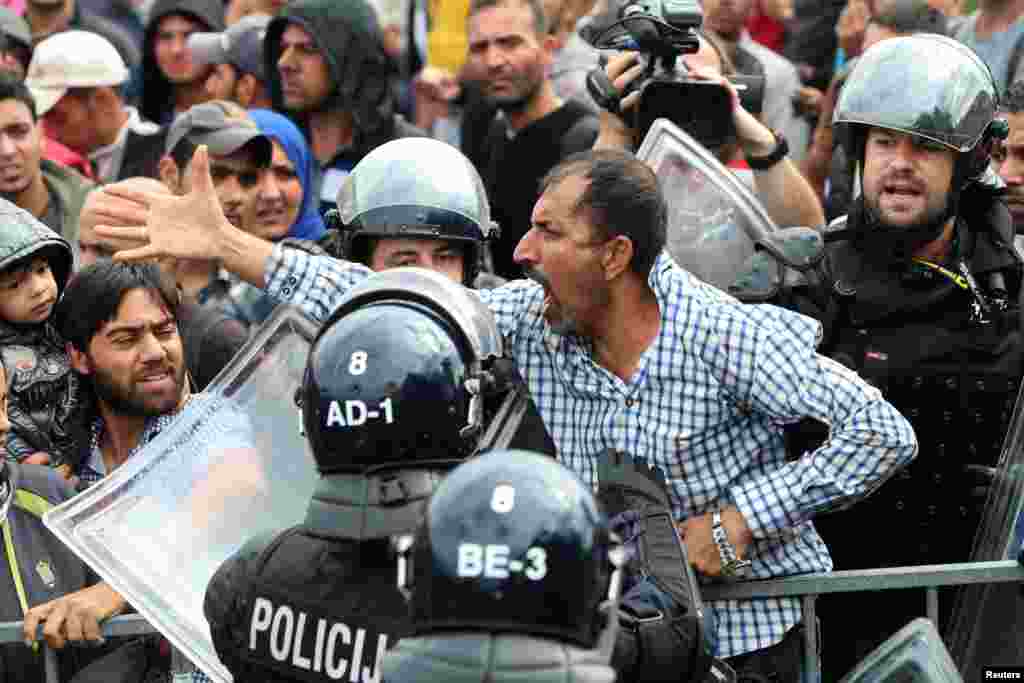A migrant man reacts as he is surrounded by Slovenian police at the Slovenia-Croatia border crossing in Rigonce, Slovenia, Sept. 19, 2015.