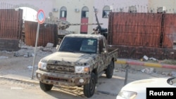 Seorang anggota pasukan keamanan yang setia kepada pemerintah Libya yang didukung PBB mengendarai pickup di penjara Al-Hadba yang rusak saat baku tembak dengan faksi saingan di distrik Abu Salim, di Tripoli, Libya, 28 Mei 2017. (Foto: Hani Amara/Reuters)