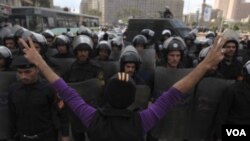 Seorang demonstran Mesir mencoba menghadang polisi anti huru-hara dalam bentrokan di Lapangan Tahrir, Kairo (19/11).