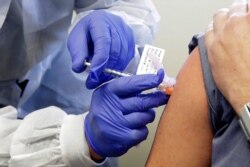 FILE - A subject receives a shot in the first-stage safety study clinical trial of a potential vaccine by Moderna for COVID-19, at the Kaiser Permanente Washington Health Research Institute in Seattle.