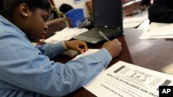 FILE - Akira Lee, a senior at Roosevelt High School, fills out a college enrollment application at her school in Washington.