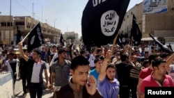 File - Demonstrators chant pro-Islamic State group slogans as they wave the group's flags in front of the provincial government headquarters in Mosul, Iraq, June 2014.
