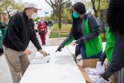 FILE - New York City Department of Parks and Recreation staff distribute free face masks at the Mauro playground in the Kew Gardens Hills neighborhood of the Queens borough of New York City, May 5, 2020.
