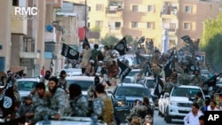 
Para kombatan kelompok teror ISIS berpawai di Raqqa, Suriah utara, 20 Juni 2014.
