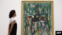 Una mujer observa una obra de arte titulada 'The Sombre Malembo 1943' del pintor surrealista cubano, Wifredo Lam, durante una sesión fotográfica para promover una exposición de la obra del artista, en la galería Tate Modern de Londres.