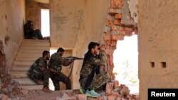 FILE - Kurdish People's Protection Units (YPG) fighters take up positions inside a damaged building in al-Vilat al-Homor neighborhood in Hasaka, Syria, as they monitor the movements of Islamic State fighters, July 22, 2015.