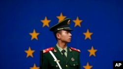Seorang polisi China berjaga di depan bendera Uni Eropa di kantor delegasi Uni Eropa di Beijing, China (Foto: dok).