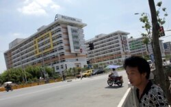 People walk near several buildings of a Pegatron factory in Shanghai, China, July 30, 2013.