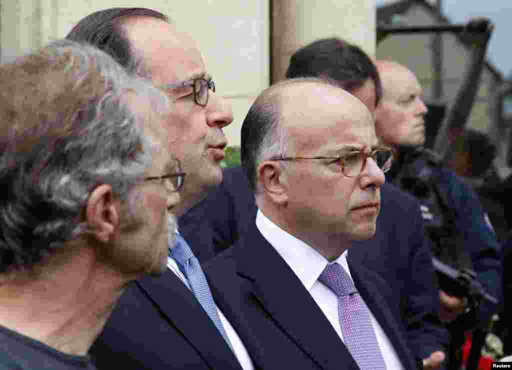 French President Francois Hollande (C) and Interior Minister Bernard Cazeneuve (R) speak to journalists in front of the city hall after two assailants had taken five people hostage in the church at Saint-Etienne-du -Rouvray near Rouen in Normandy, France on July 26, 2016. 