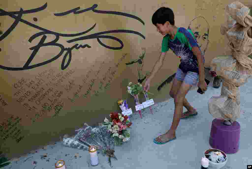 A boy places flowers on a wall with an image and signature of former NBA basketball player Kobe Bryant at the 'House of Kobe' basketball court in Valenzuela, north of Manila, Philippines on Jan. 27, 2020.