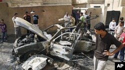 People inspect a car destroyed after a bomb attached to it exploded in Basra, Iraq's (File)