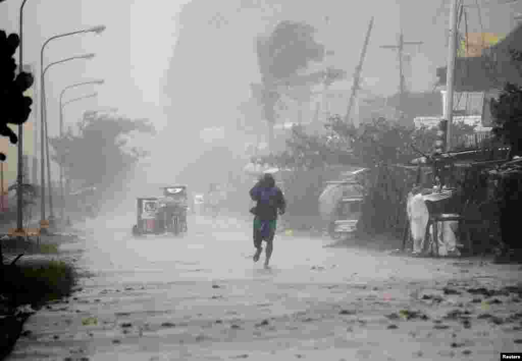 A man walks on a street while strong winds and heavy rain, brought by typhoon Hagupit, batter Atimonan town, Quezon province, south of Manila, December 8, 2014.