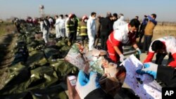 FILE - A rescue worker shows pictures of a girl recovered from a Ukrainian plane crash site in Shahedshahr, southwest of the capital Tehran, Iran.