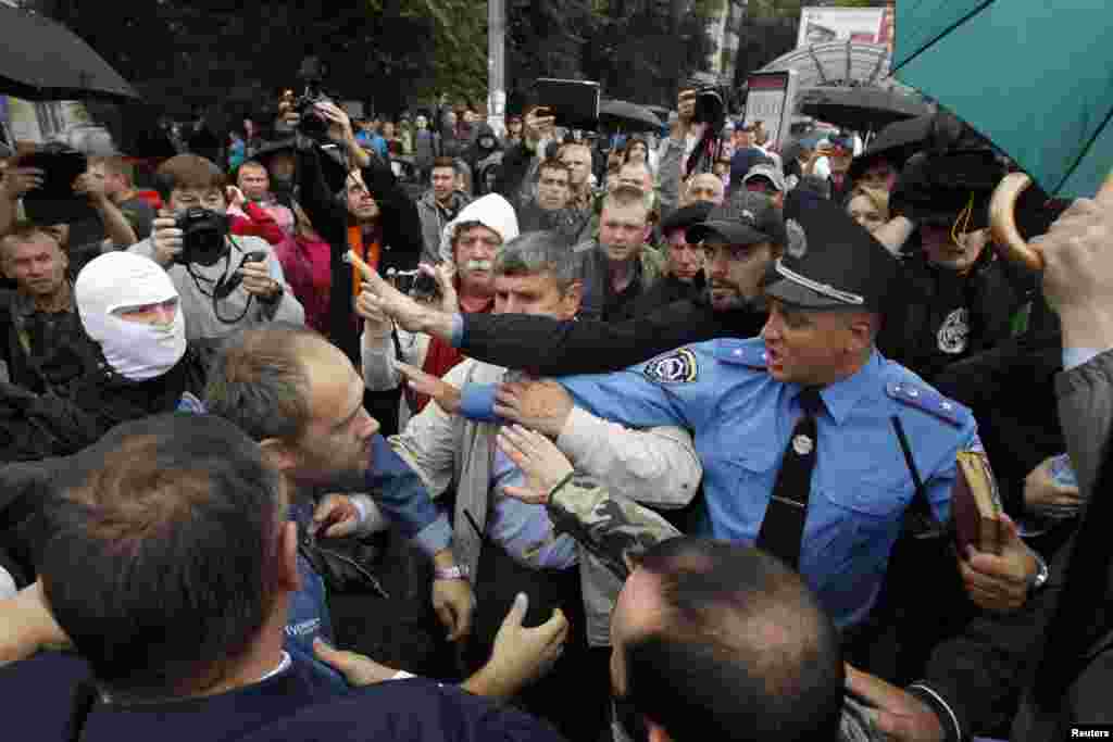 A police officer tries to prevent activists and relatives of Ukrainian soldiers from getting into the defense ministry building during a protest, in Kyiv, Aug. 28, 2014. 