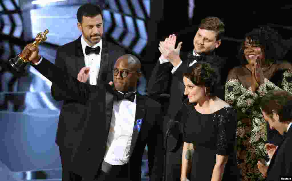Sutradara dan penulis Barry Jenkins memegang piala Oscar untuk film terbaik bagi "Moonlight", didampingi oleh para aktor dan aktris film itu.