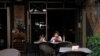 FILE - A woman wearing a protective mask sits outside a bar during a power cut in Beirut, Lebanon, Aug. 16, 2021.