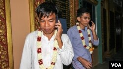 Former Radio Free Asia journalists Uon Chhin and Yeang Sothearin are seen talking on their cell phone after being released on bail in Phnom Penh, Cambodia, August 21, 2018. (Aun Chhengpor/VOA Khmer) 