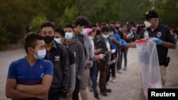 FILE - Unaccompanied minors from Central America line up to be transported by U.S. Customs officials, after crossing the Rio Grande into the United States from Mexico on rafts, in Penitas, Texas, March 26, 2021.