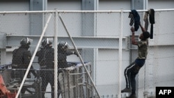 ARCHIVES - Un jeune tente d'escalader la clôture frontalière dans l'exclave espagnole de Ceuta, à la frontière avec le Maroc, le 13 avril 2021. 