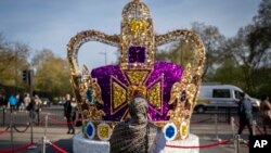 Une femme prend des photos d'une installation artistique représentant la couronne de Saint Édouard à Londres, le mercredi 3 mai 2023.