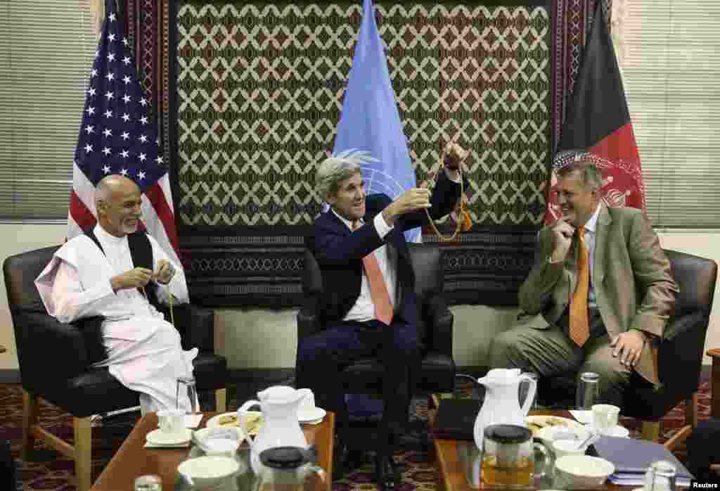 U.S. Secretary of State John Kerry (center) holds up a string of Islamic beads, as Afghanistan's presidential candidate Ashraf Ghani Ahmadzai (left) and Jan Kubis, the U.N. Secretary-General's special representative look on, during a meeting at the U.S. embassy in Kabul, Aug. 8, 2014.