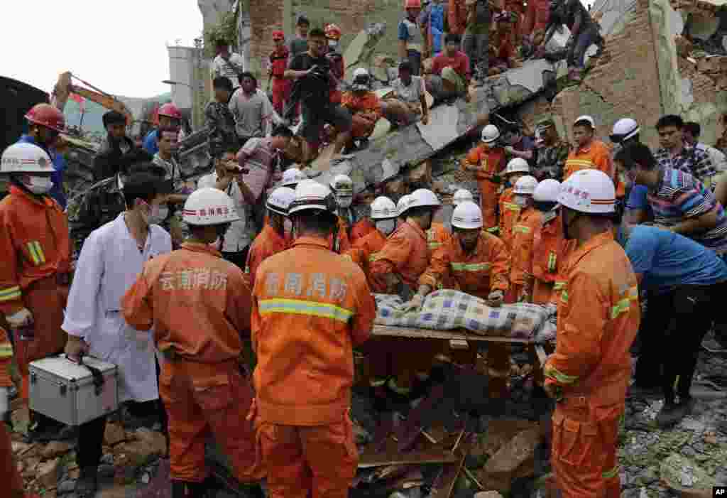 Rescuers prepare to carry away a young victim on a stretcher near a destroyed house following a massive earthquake in the town of Longtoushan in Ludian County in southwest China's Yunnan Province, Aug. 5, 2014.