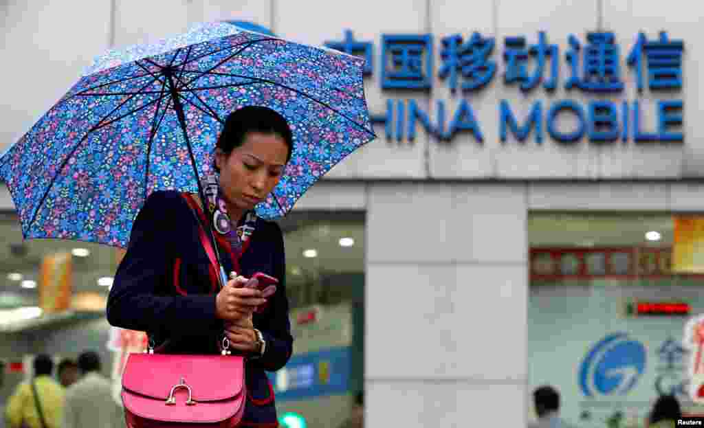 一名妇女在上海市的中国移动公司分支机构前使用手机(2012年10月22日)