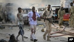 FILE - A Somali soldier helps a civilian who was wounded in a blast in the capital of Mogadishu, Oct. 14, 2017. 