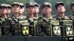 FILE- North Korean soldiers turn and look towards their leader Kim Jong Un from a military parade vehicle as they carry packs marked with the nuclear symbol during a ceremony marking the 60th anniversary of the Korean War armistice in Pyongyang, North Kor