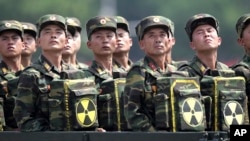 FILE- North Korean soldiers turn and look towards their leader Kim Jong Un from a military parade vehicle as they carry packs marked with the nuclear symbol during a ceremony marking the 60th anniversary of the Korean War armistice in Pyongyang, North Korea.