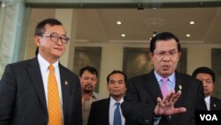 PM Kamboja Hun Sen (kanan) bersama Sam Rainsy, pemimpin partai CNRP (kiri), seusai pemilihan anggota Komisi Pemilu Baru di Phnom Penh, Kambojia, 9 April 2015.
