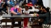FILE - Migrants pass the time at a migrant shelter, May 12, 2021, in McAllen, Texas. Migrants from four countries were among those who rode a bus from Texas to Washington, D.C., that arrived Wednesday.