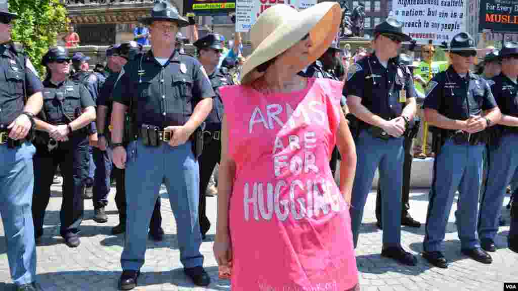 Woman stands in front of police in a shirt reading "Arms are for Hugging" at the Republican National Convention in Cleveland (July 19, 2016).