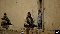 FILE - British soldiers from the Nato-led International Security Assistance Force patrol as Afghan kids look on in the outskirts of Kabul, Afghanistan.