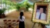 In this Nov. 20, 2016 photo, a girl stands by a portrait of Kem Ley, a Cambodian prominent political analyst, at his grave in Ang Takok, Cambodia. Kem Ley, a poor rice farmer's son turned champion of Cambodia's have-nots, was sipping his usual iced latte in the same chair he had occupied most mornings for years when a former soldier he may never have met walked into the Caltex gas station cafe. Armed with a semi-automatic Glock pistol, the assassin fired into his chest and head, execution-style. Then he walked casually away from the scene. (AP Photo/Denis Gray)