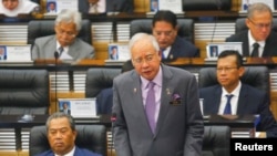 FILE - Malaysia's Prime Minister Najib Razak (R) delivers a speech next to Deputy Prime Minister Muhyiddin Yassin during a special parliamentary session convened to discuss the MH17 tragedy at the Parliament House in Kuala Lumpur.