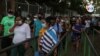 Trabajadores salen de una empresa privada en Managua, unos con máscaras, otros sin ellas. Foto VOA.