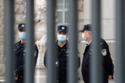 Policemen wearing face masks chat each other at No. 2 Intermediate People's Court in Beijing, March 22, 2021.