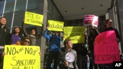 Protesters hold up signs outside a courthouse, April 14, 2017, where U.S. District Court Judge William Orrick ruled on a lawsuit challenging President Donald Trump's executive order to withhold funding from sanctuary cities.
