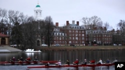 FILE - Rowers pass the campus of Harvard University as they move down the Charles River in Cambridge, Mass., March 7, 2017. Harvard and the group Students for Fair Admissions will go to trial in a lawsuit alleging discrimination against Asian-American ap