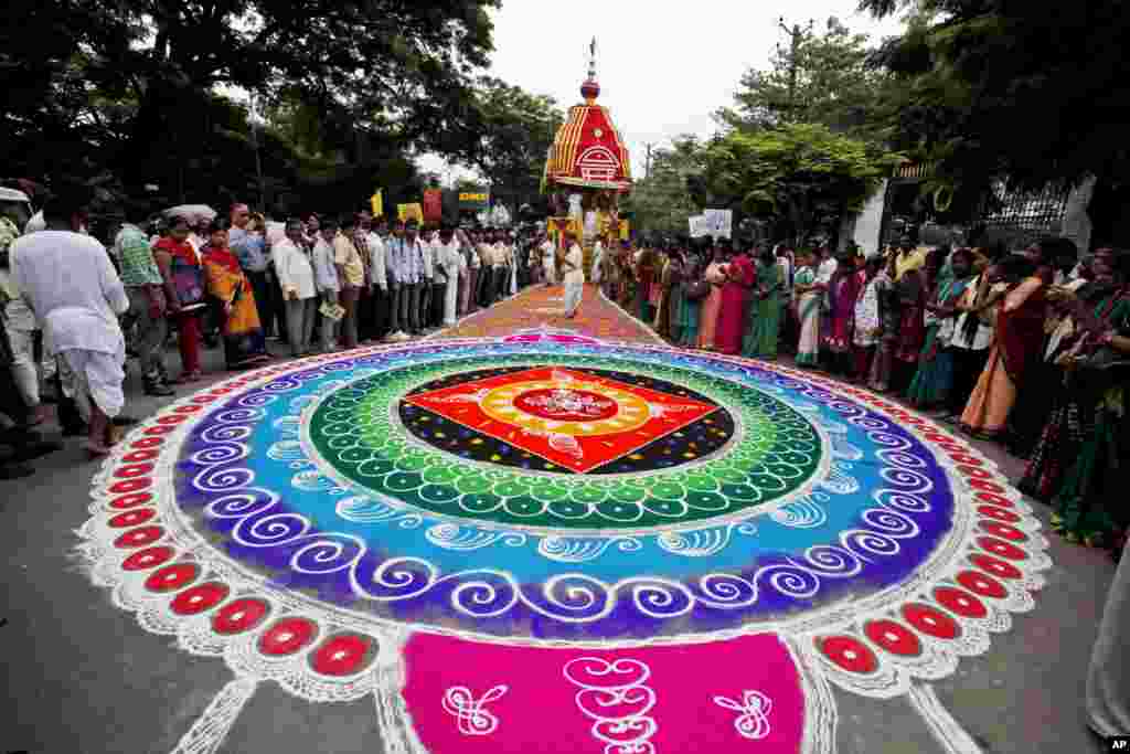 Umat Hindu berdiri di sekitar karya seni tradisional yang terbuat dari bubuk berwarna selama festival tahunan Rath Yatra di Hyderabad, India.