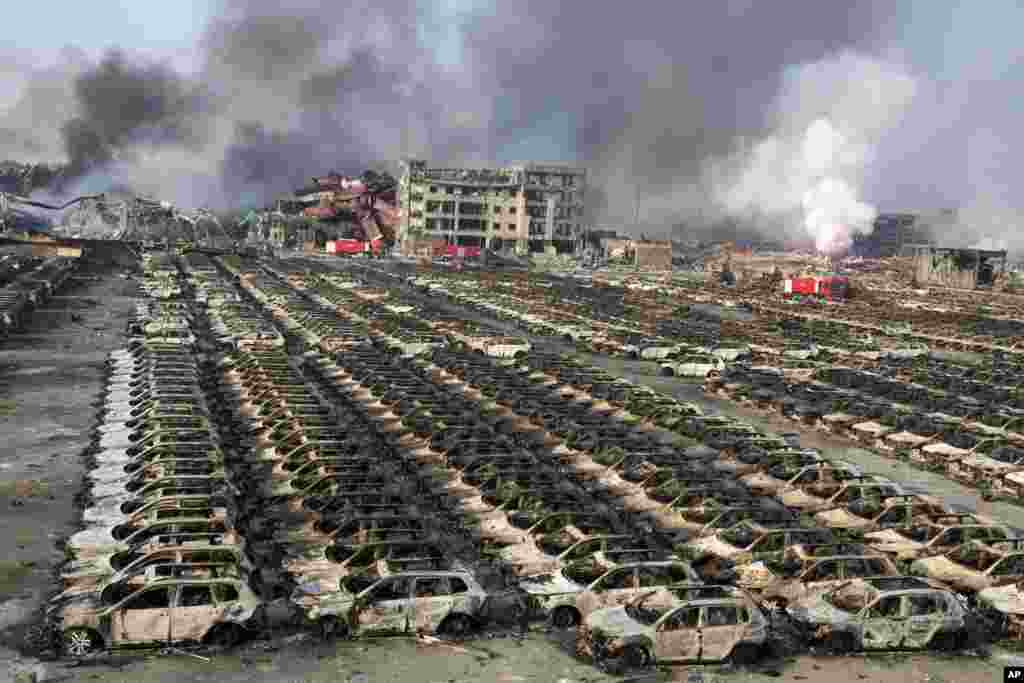 Smoke billows out from the site of an explosion that reduced a parking lot filled with new cars to charred remains at a warehouse in northeastern China's Tianjin municipality, Aug. 13, 2015. Huge explosions in the warehouse district sent up massive fireballs that turned the night sky into day in the port city, officials and witnesses said.