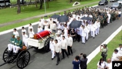 In this photo provided by the Office of Ilocos Norte Governor Imee Marcos, Imelda Marcos, in black on a wheelchair under an umbrella, the widow of the late dictator Ferdinand Marcos, and their close relatives follow the flag-draped casket of Ferdinand Marcos, and their close relatives follow the flag-draped casket of Ferdinand Marcos during a ceremony of his burial at the Heroes' Cemetery in suburban Taguig city, Philippines, Nov. 18, 2016. 