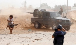 FILE - A journalist covers the frontline during clashes between forces loyal to strongman Khalifa Haftar and fighters loyal to the Libyan internationally-recognized Government of National Accord, south of Tripoli, May 25,2019.
