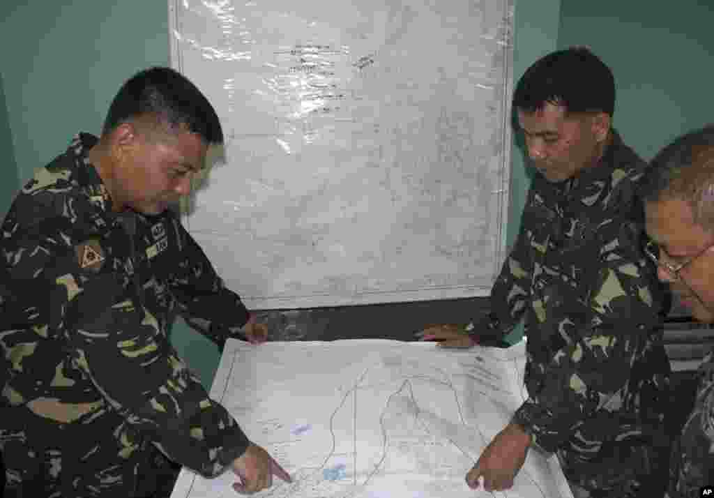 In this photo released by the Armed Forces of the Philippines, Western Command PIO, Filipino government troopers look at a map as they continue the search for the missing plane of Malaysian Airlines at Antonio Bautista Air Base in Puerto Princesa City, Palawan province.